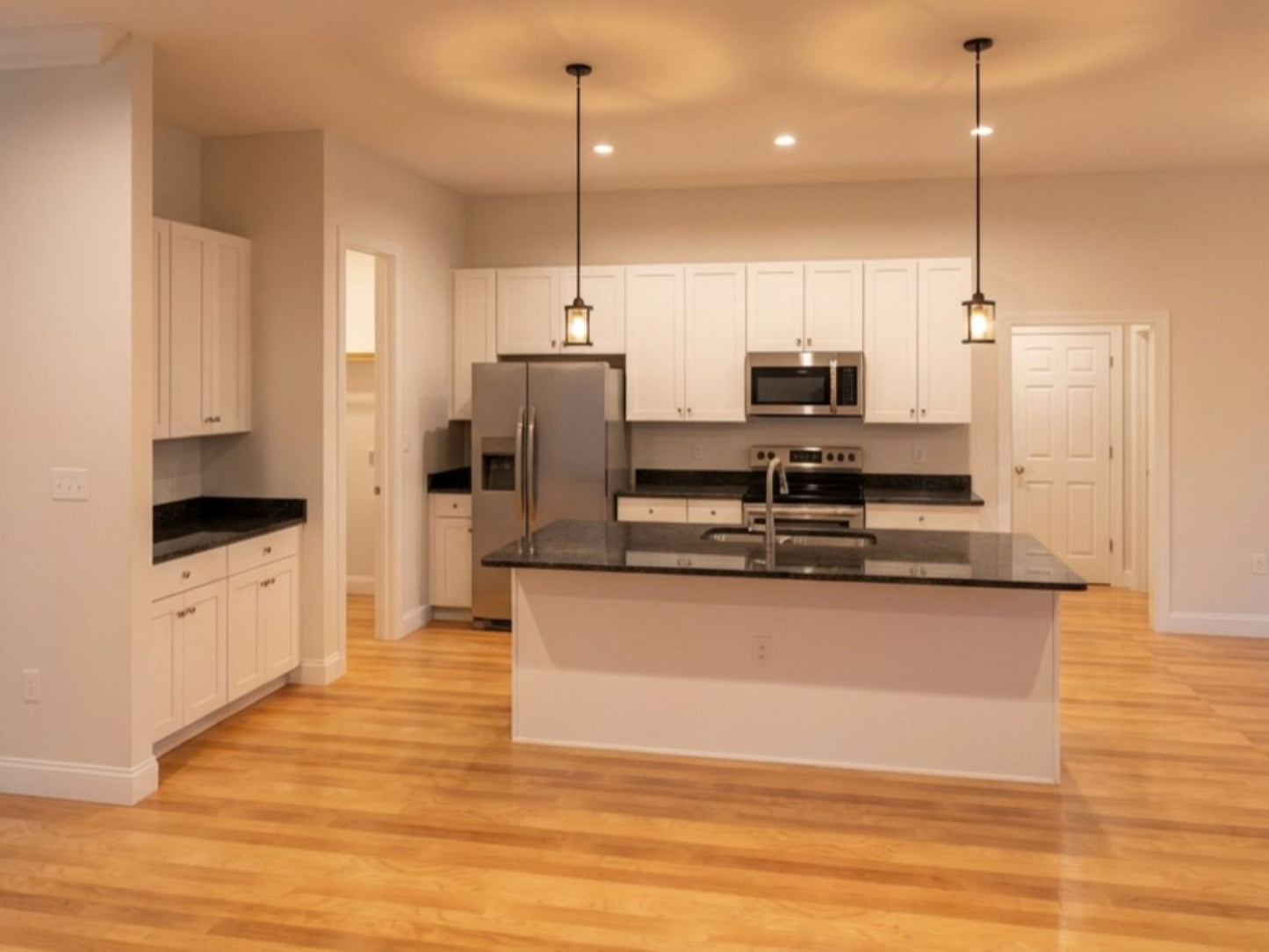 Meadowbrook house plan open kitchen with large island, white cabinets, and modern lighting